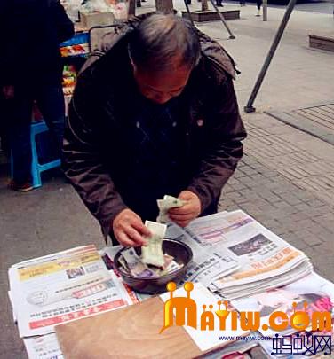 一位老人在选购报纸后找补钱